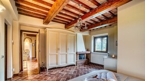 A bedroom with a large bed, a fireplace, and a window. - Cosy and roomy apartment of 110 sqm for 6 persons on the 1st floor of a rustic-style farmhouse (NO lift or stairs for access), immersed in the Umbrian countryside.The accommodation consists of a kitchen, a living room, three bedrooms, two bathrooms and t (Castiglione del Lago)
