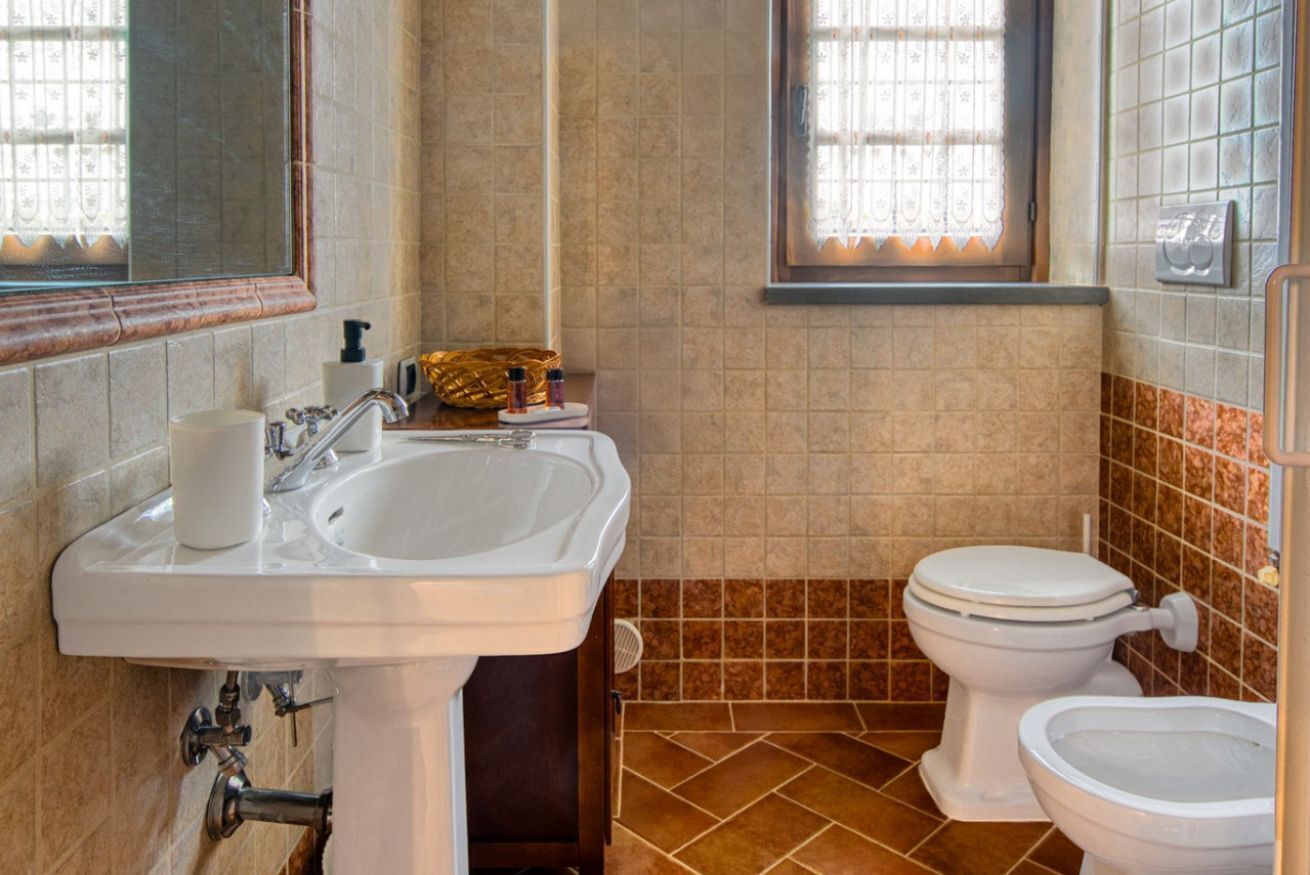 A bathroom with a sink, toilet, and window.