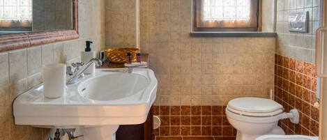 A bathroom with a sink, toilet, and window.