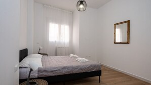 Une chambre à coucher avec un lit, une lampe de chevet, une table ronde et un luminaire suspendu.
