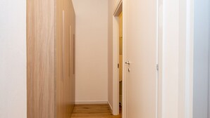 Un couloir étroit avec un plancher en bois et des murs blancs.