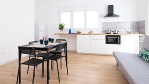 Une cuisine moderne avec des armoires blanches, une hotte noire et un coin repas comprenant une table et des chaises.