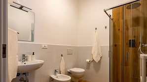 Une salle de bain équipée d’un lavabo, d’un bidet, de toilettes et d’une douche à parois de verre.