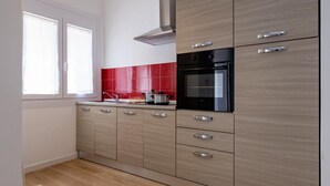 A modern kitchen with light wood cabinets, a black oven, and a red backsplash. - GuestHost - Cozy 55 sqm apartment, for 4 people, located on the ground floor of a modern building. The property is located in a strategic area of ​​Piombino, an ideal starting point for exploring the city and the Tuscan coast. A few minutes from the  (Piombino)