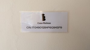 A white sign with 'Casa Matisse' and a CIN code. - GuestHost - Cozy 40 sqm studio, for 4 people, located on the ground floor of a modern building. The property is located in a strategic area of ​​Piombino, an ideal starting point for exploring the city and the Tuscan coast. A few minutes from the his (Piombino)
