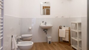A modern bathroom with a toilet, bidet, sink, and a mirror. - GuestHost - Cozy 40 sqm studio, for 4 people, located on the ground floor of a modern building. The property is located in a strategic area of ​​Piombino, an ideal starting point for exploring the city and the Tuscan coast. A few minutes from the his (Piombino)
