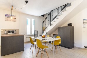 Une cuisine moderne avec un coin repas, un escalier et une vue sur l’extérieur.