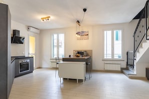 Une cuisine moderne dotée d’un four encastré, d’une table à manger avec des chaises et d’un escalier situé sur le côté droit.