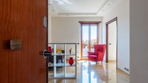 A modern living room with a glass partition, a red chair, and a door leading to a balcony. - GuestHost - Bright apartment of about 100 sqm, perfect for 3 people, located on the seventh floor of a building with elevator (NOT suitable for disabled people - some steps to access it).The property is located in a quiet residential area well connected  (Rome)