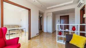 A modern living room with a sofa, a red chair, a white shelving unit, and a dining area with a table and chairs. - GuestHost - Bright apartment of about 100 sqm, perfect for 3 people, located on the seventh floor of a building with elevator (NOT suitable for disabled people - some steps to access it).The property is located in a quiet residential area well connected  (Rome)