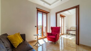 A spacious living area with a brown leather sofa, a red armchair, and a small round table. - GuestHost - Bright apartment of about 100 sqm, perfect for 3 people, located on the seventh floor of a building with elevator (NOT suitable for disabled people - some steps to access it).The property is located in a quiet residential area well connected  (Rome)