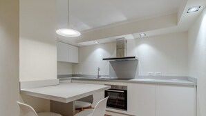 A modern kitchen with white cabinetry, a built-in oven, and two white chairs. - GuestHost - 80 sqm apartment for 3 people, located on the ground floor (steps required for access). Just a 6-minute drive from Caprafico Beach, the accommodation is in Nervi, one of the most charming districts of Genoa, known for its parks, historic vill (Genova)