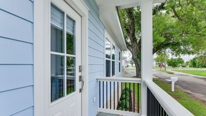A house with a porch, a white door, and a tree in the background. - Walk to Beach & Harbor: Dtwn Pass Christian Home (Pass Christian)