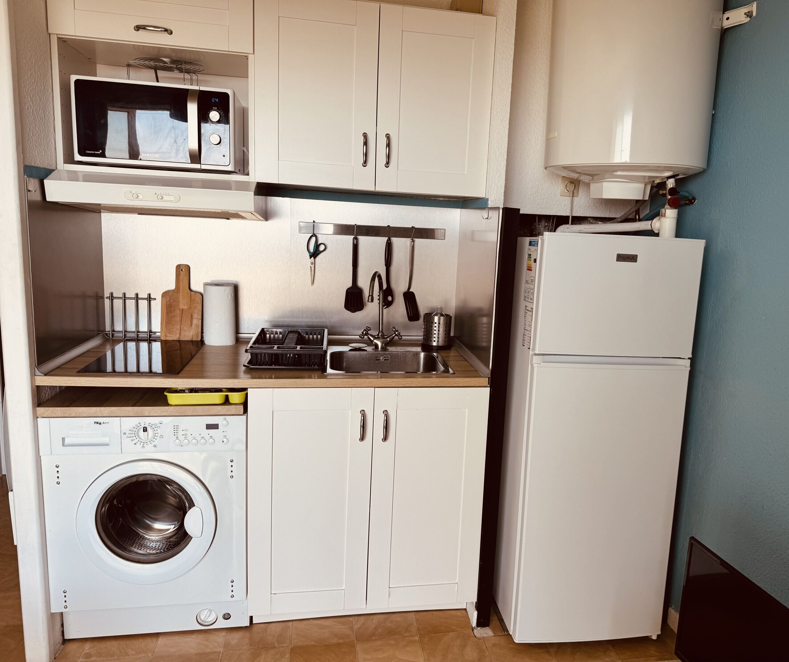 A compact kitchen with a microwave, sink, and refrigerator.