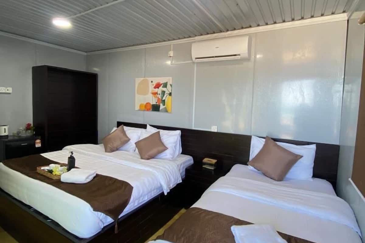 Quarto de hotel com duas camas, soalho de madeira, aparelho de ar condicionado e um quadro na parede.