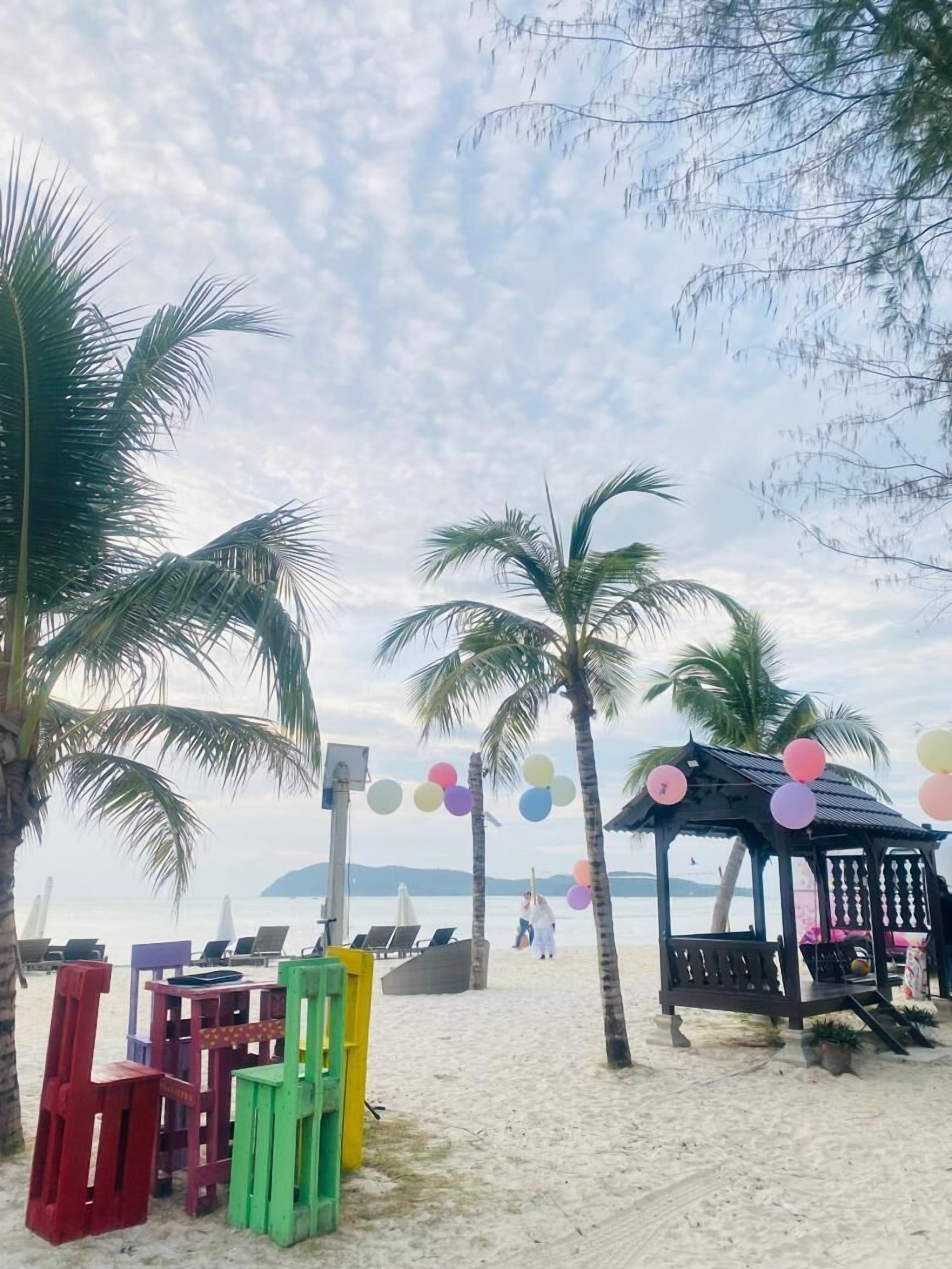 A beach with palm trees, a gazebo, and colorful balloons.