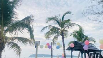 Una playa con palmeras, un pabellón y coloridos globos.
