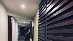 A hallway with a staircase, wooden slats on the wall, and tiled flooring. - Hidden Negombo by Sana's (Negombo)