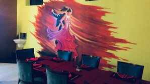 A dining area with a mural of a couple dancing, a tiled floor, and a yellow wall. - Hidden Negombo by Sana's (Negombo)