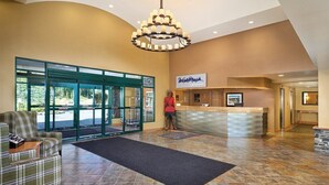A reception area with a receptionist, a reception desk, and a view of the outside through glass doors.