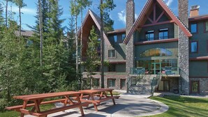 A lodge with a stone facade, multiple balconies, and a central glass entryway.