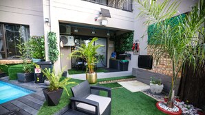 Un giardino con piscina, prato sintetico e mobili da esterno.