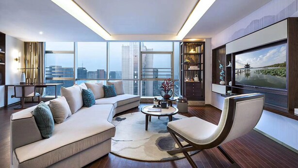 A modern living room with a sectional sofa, a round coffee table, and a large TV screen. - Hangzhou Binjiang Qianchao New Century Hotel (Hangzhou)