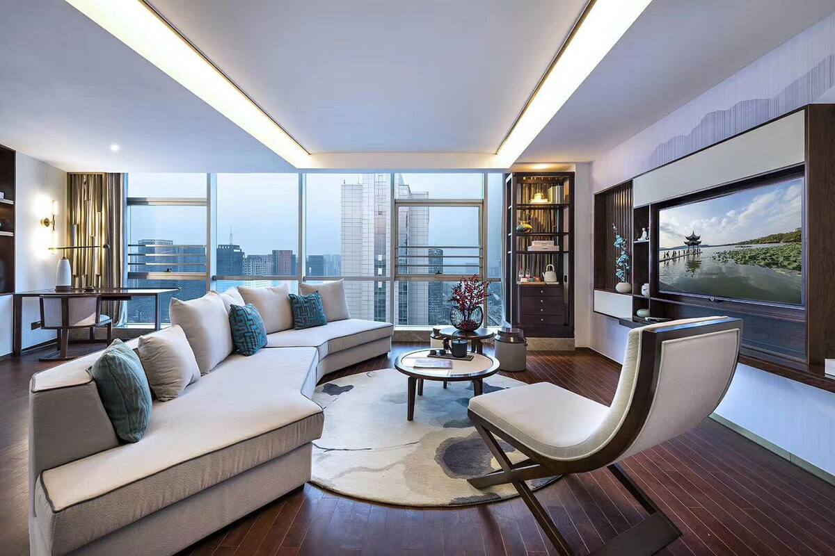 A modern living room with a sectional sofa, a round coffee table, and a large TV screen.