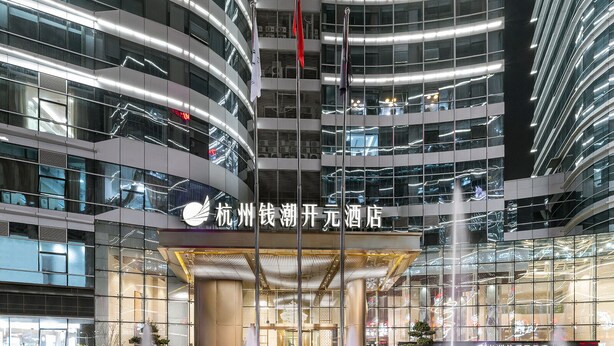 A modern hotel with a glass facade, multiple floors, and a central entrance with a canopy.
