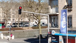 Une vue de rue avec un feu de circulation, un passage piéton et un immeuble portant une enseigne de l’agence immobilière Guy Hoquet.