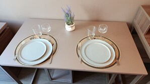 Une table à manger dressée avec des assiettes, des couverts et des verres, et une petite plante en pot posée sur la table.