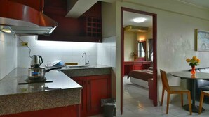 A kitchen with a granite countertop, a stove, and a sink. There is a dining area with a table and chairs, and a bedroom with a bed and a dresser. - Petch Tower Ekkamai (Bangkok)