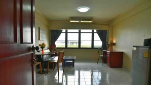 A hotel room with a dining area, a refrigerator, and a window with curtains. - Petch Tower Ekkamai (Bangkok)