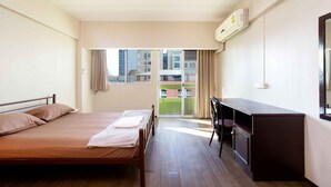 A hotel room with a bed, desk, and a view of buildings through the window. - Petch Tower Ekkamai (Bangkok)