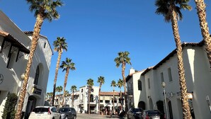 A street lined with palm trees and white buildings with arched windows. - Sun-Soaked Condo near Old Town (La Quinta)