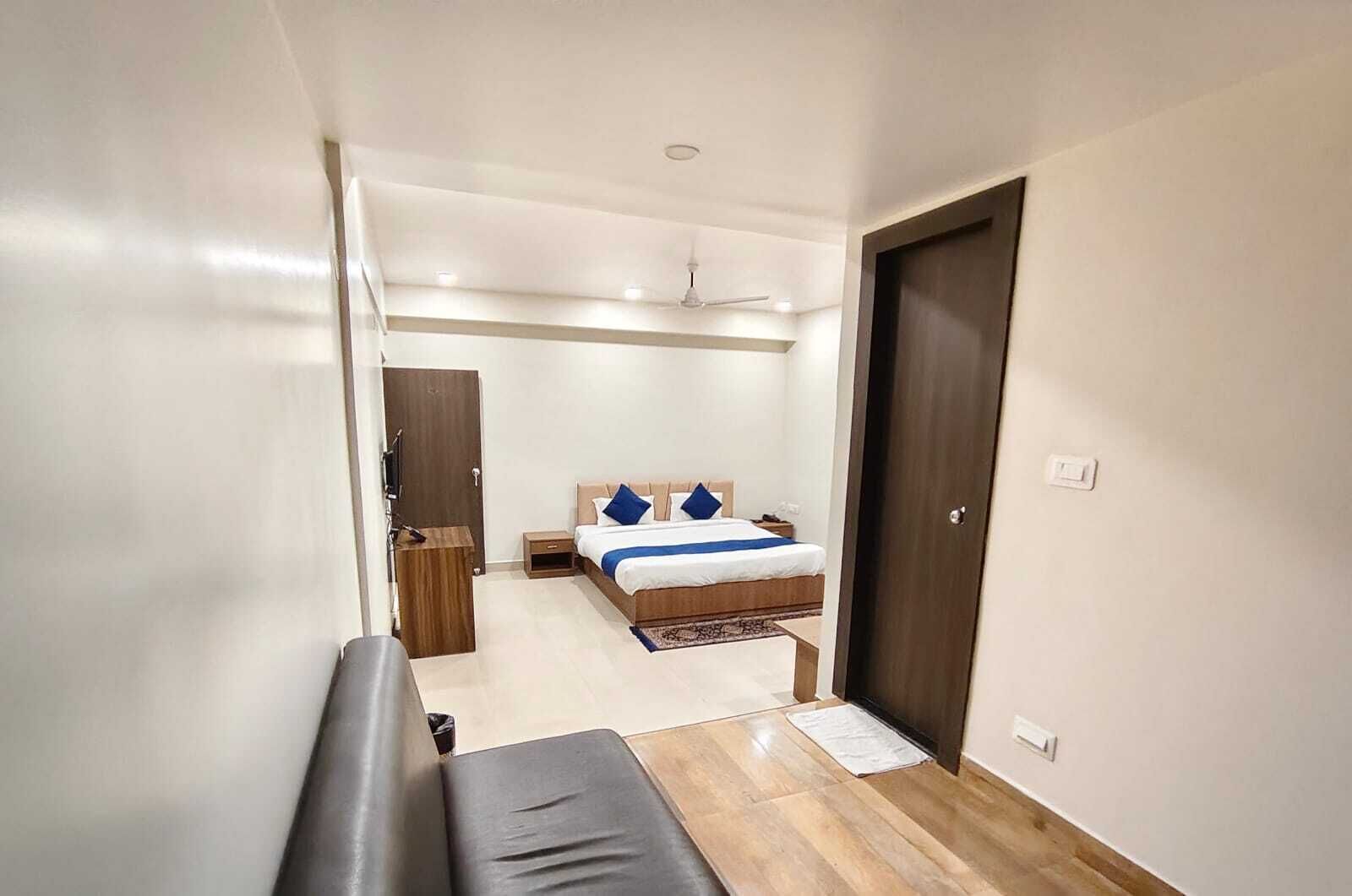 A hotel room with a bed, a desk, a chair, a wardrobe, and a door.