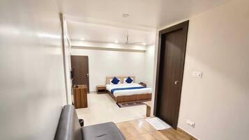 A hotel room with a bed, a desk, a chair, a wardrobe, and a door.