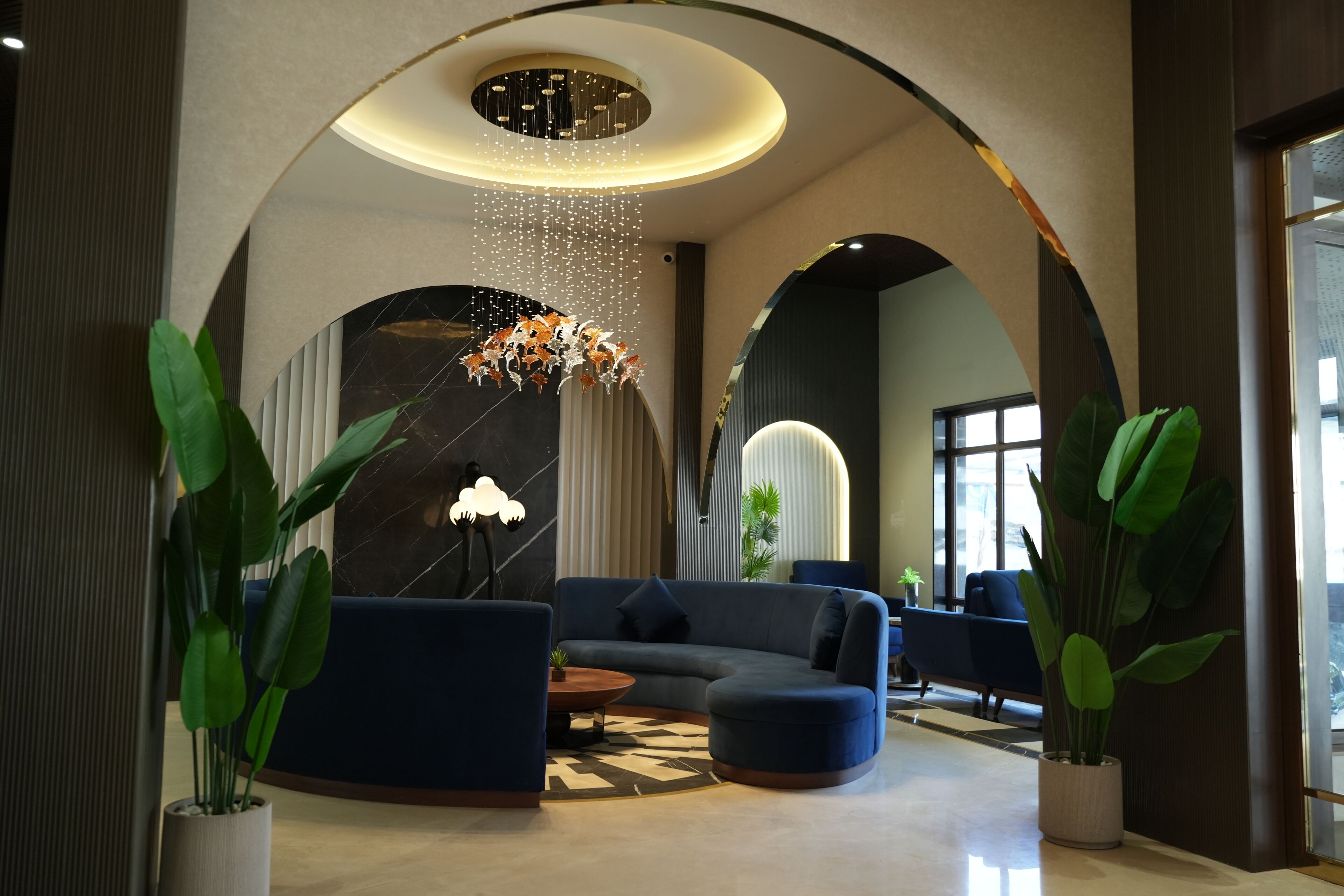A modern lobby with a curved ceiling, seating area, and potted plants.