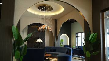 A modern lobby with a curved ceiling, seating area, and potted plants.