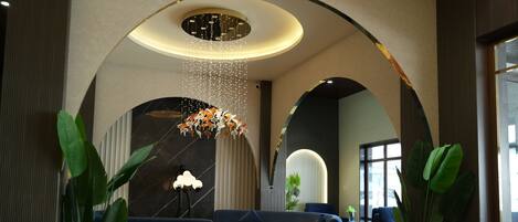 A modern lobby with a curved ceiling, seating area, and potted plants.
