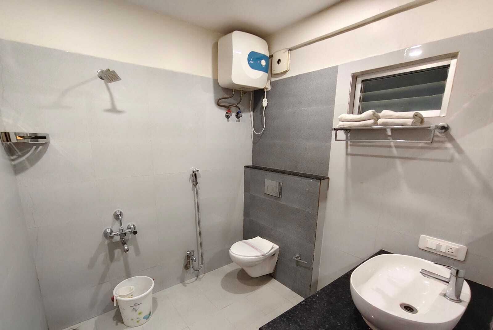 A bathroom with a toilet, bidet, shower, sink, and towel rack.