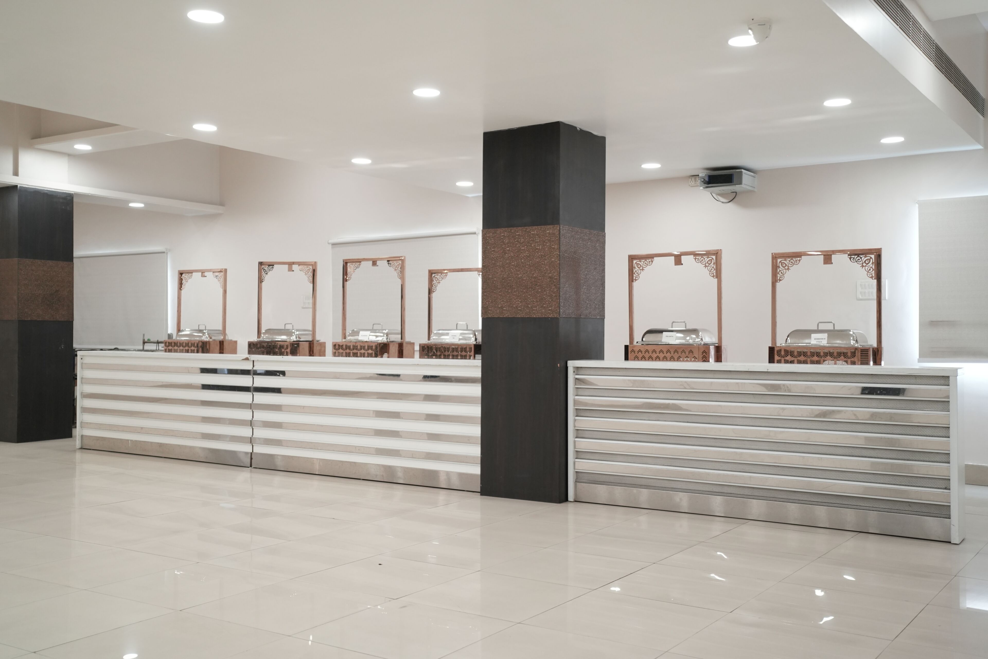 Un moderno vestíbulo de hotel con mostrador de recepción, varios espejos y un piso de baldosas limpias.
