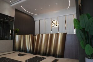 A reception area with a modern design, featuring a reception desk with a metallic finish and a large illuminated 'S' sign. - SAROVAR HILL HOTEL AND RESORT (Jamshedpur)