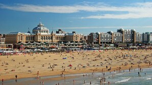 Una playa con un edificio grande al fondo.