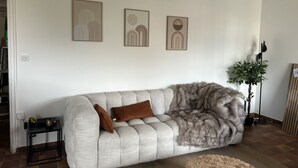 Una sala de estar con un sofá, una mesita y tres obras de arte enmarcadas en la pared.