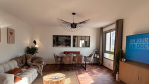 Una sala moderna con sofá, mesa de comedor, sillas y televisor.