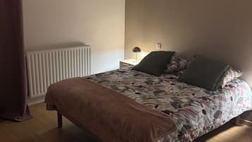 A bedroom with a bed, a radiator, a lamp, and a hanging light fixture.