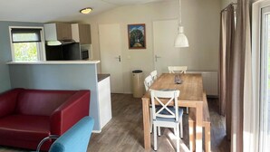 A compact living space with a kitchenette, a dining area, and a red sofa.