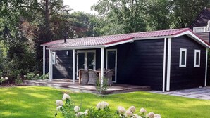 A modern house with a covered porch, a well-maintained lawn, and flowering plants.