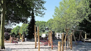 A playground with wooden structures and a sandy ground.